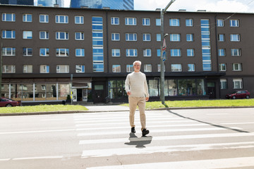 senior man walking along city crosswalk