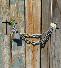 Wooden door closed with padlock and chain