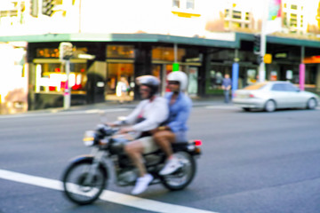 Motion Blur Motorcycle Rider and Passenger on city street in Sydney Australia. Motor bike driving past in urban environment.
