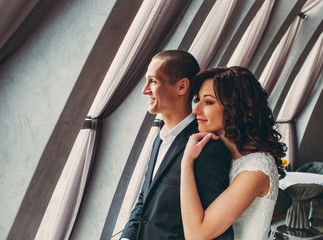 The lovely couple in love embracing near window