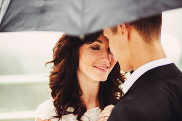 The brides with umbrella embracing on the balcony