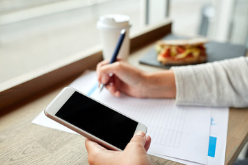 woman with smartphone and paper form at cafe