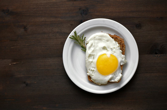 fried egg with rosemary on a white plate