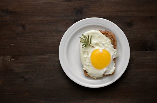 fried egg with rosemary on a white plate