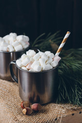Two mugs with cocoa and marshmallows on a brown background