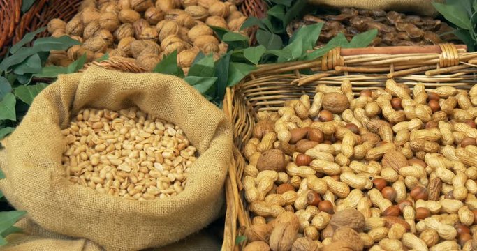 Different nuts in baskets and sacks on wooden shelf