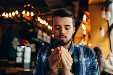 Young man is sitting in the restaurant and tasting a warm drink.