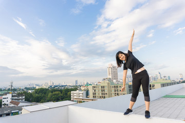 Fitness runner body doing warm-up routine on roof top building b