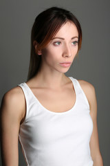 Girl with red hair in tanktop. Close up. Gray background