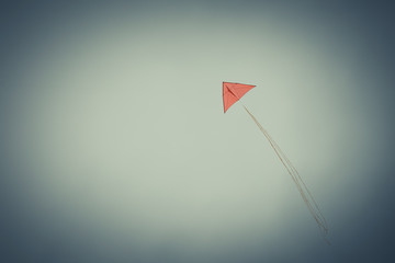 A red, triangle kite in the sky. Vignette effect. Blue toned.