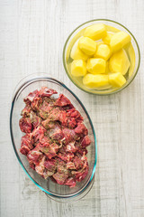 Raw sliced meat and potatoes  on the glass bowls vertical