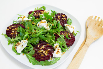 Salad of baked beet, homemade goat cheese, arugula and pine nuts, selective focus