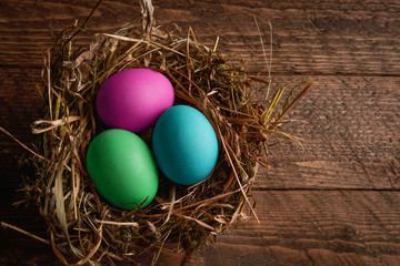 painted Easter eggs in a wicker straw nest on wooden backgroundpainted Easter eggs in a wicker straw nest on wooden background
