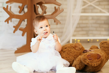 Fototapeta premium baby girl with a soft brown teddy bear in the interior with Chri