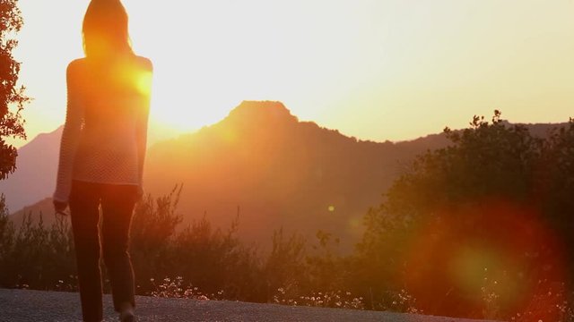 femme marchant au coucher du soleil sur une montagne