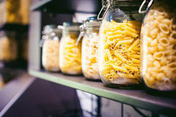 pasta in the jar. on kitchen shelves are different kinds of pasta in glass jars