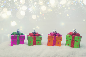 Row of Christmas presents in snow with lights bokeh in background, retro toned