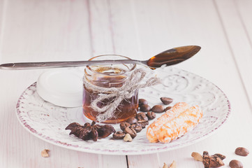 small jar with honey on a vintage saucer decorated with seeds of anise and cardamom coffee