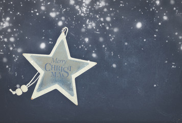 Merry Christmas star on black wooden background with copy space and snow