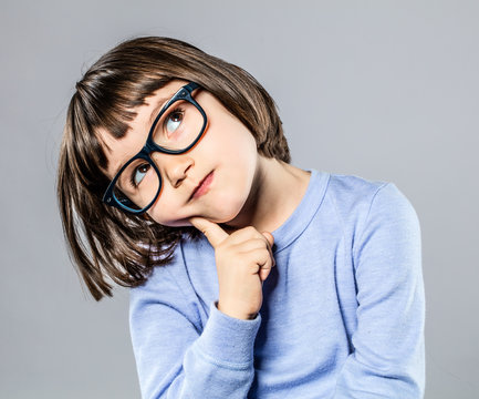 thoughtful beautiful little girl with intelligent eyeglasses to imagine