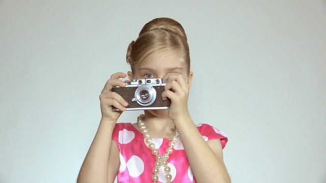 The girl holds the old camera in hands