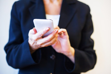 Woman hands holding white mobile phone. Closeup.