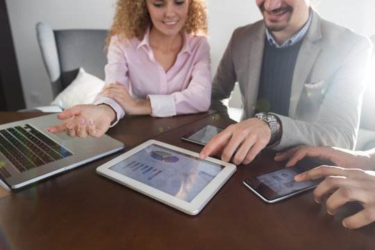 Business People Team Group Discussing Financial Diagram Report On Tablet Screen Businesspeople Meeting Sitting At Desk Coworkers Office Pointing Ginger Graph
