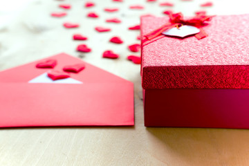 Red hearts with envelope and gift box on wooden background