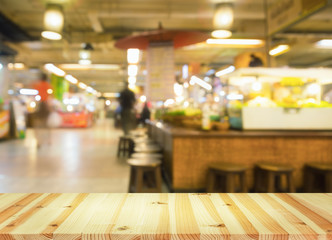 Defocused or blurred photo of food court montage with wood table top use for background.