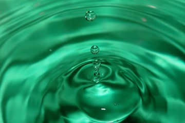 Naklejka na ściany i meble Green water drop with waves on the surface.