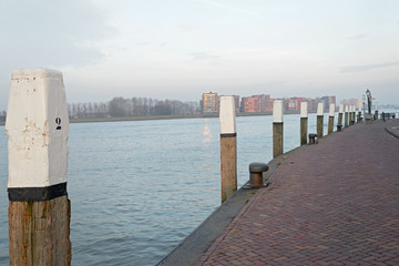 Quay along the Niewe Merwede with woorden bollard poles with whi