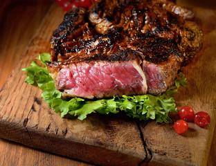 Steak with herbs and beer on a wooden background