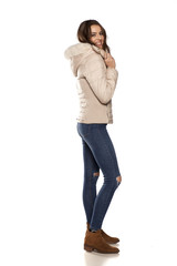 profile of young woman in a winter jacket and jeans on the white background