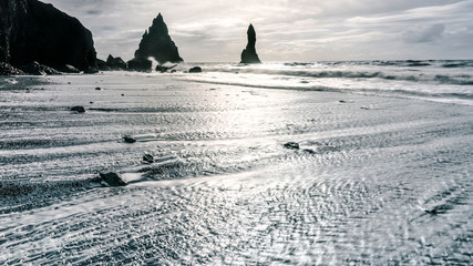Reynisfjara black sand beach in Southern Iceland. Out in the sea are the basalt sea stacks called Reynisdrangar.