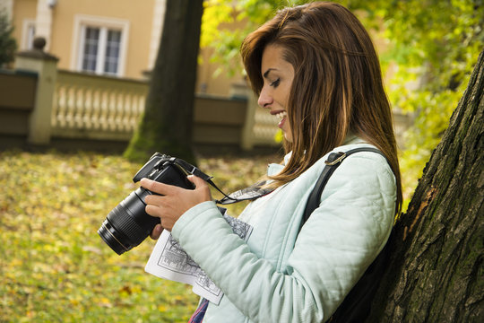 Young girl holding a camera and laughing at the park.