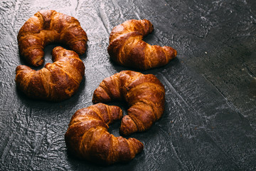 Food background: Freshly baked croissants on dark texture table with copyspace