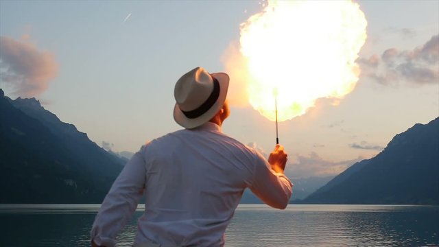 fire eater spitting fire outdoors in front of lake at night. beautiful lifestyle background