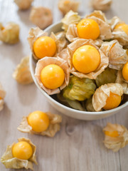 Fresh Cape gooseberry in white bowl and on wooden board