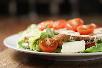 caesar salad with cherry tomatoes on wooden table
