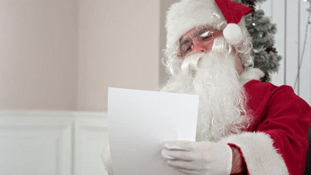 Santa Claus finishing writing and checking his letter to a kid