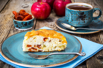 Apple cake with dried apricots on a background of old gray board