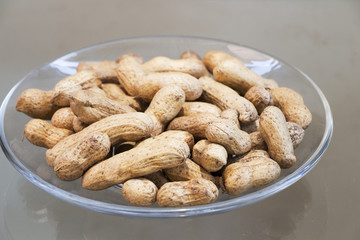 Peanuts in a glass dish on the floor.