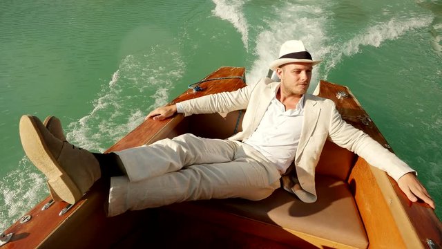 young caucasian man relaxing on boat deck wearing white casual suit. happiness lifestyle background.