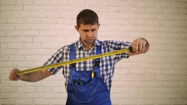 Construction worker with a tape measure.  Worker, builder, engineer with construction tape. Man measuring construction tape.