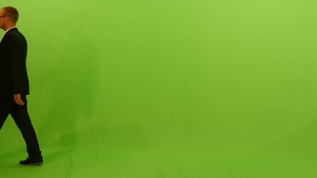 young caucasian businessman walking across frame against green screen background.
