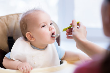 Mother gives baby food from a spoon