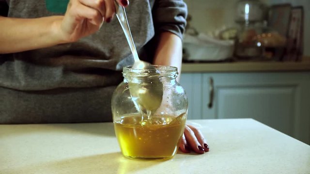 Cooking curd casseroles. Female hands stirring honey into jar with a tablespoon. HD