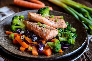 Fried salmon steaks with steamed carrot, broccoli, onion and spinach