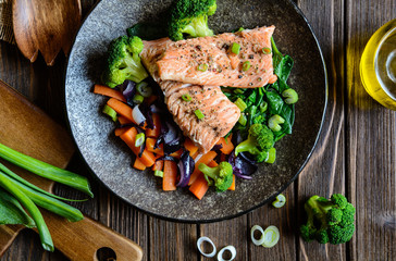 Fried salmon steaks with steamed carrot, broccoli, onion and spinach
