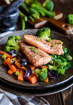 Fried salmon steaks with steamed carrot, broccoli, onion and spinach